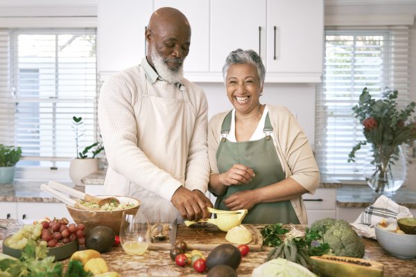 Shot of a happy mature couple having fun in the kitchen whilst making a salad and fresh orange juice